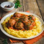 Piatto di polpette al sugo di lenticchie con polenta su tavolo in legno