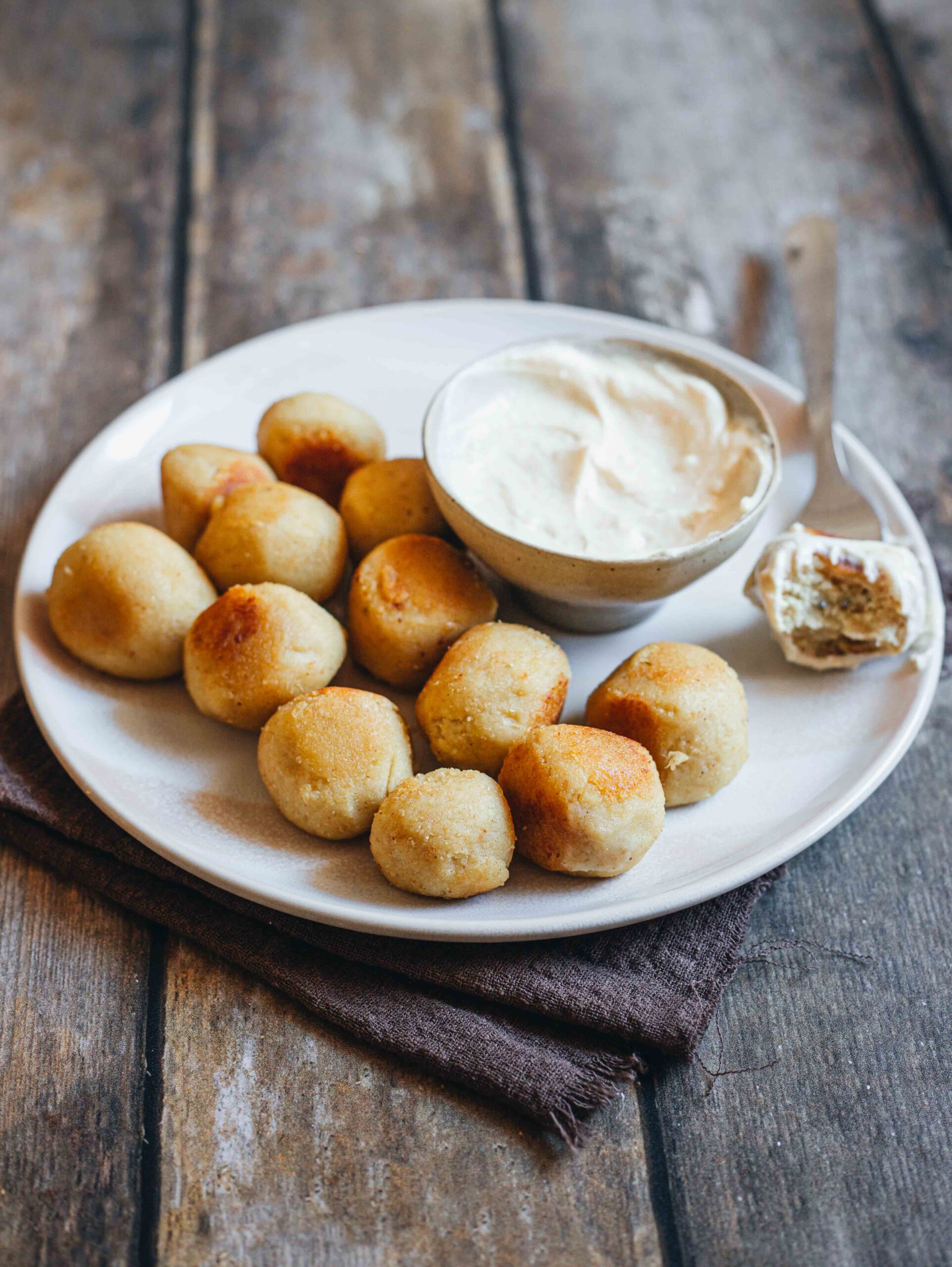 Piatto di polpette cavolfiore e patate con ciotola di maionese su tavolo in legno