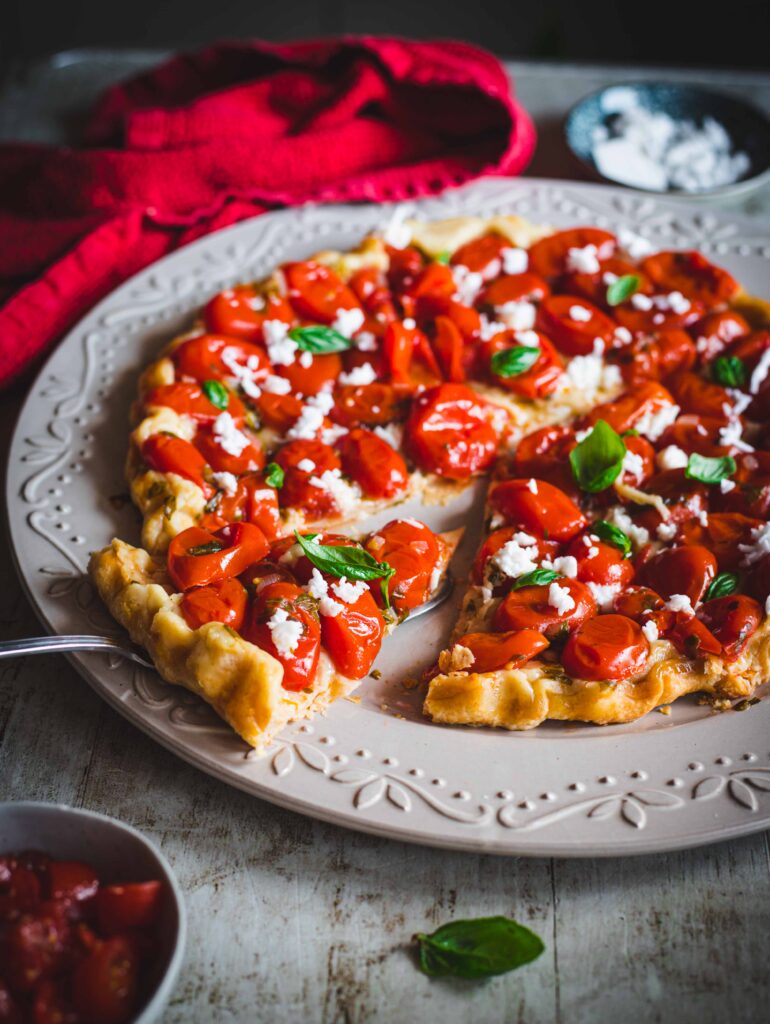 tarte tatin con pomodorini e feta su piatto bianco con fetta tagliata