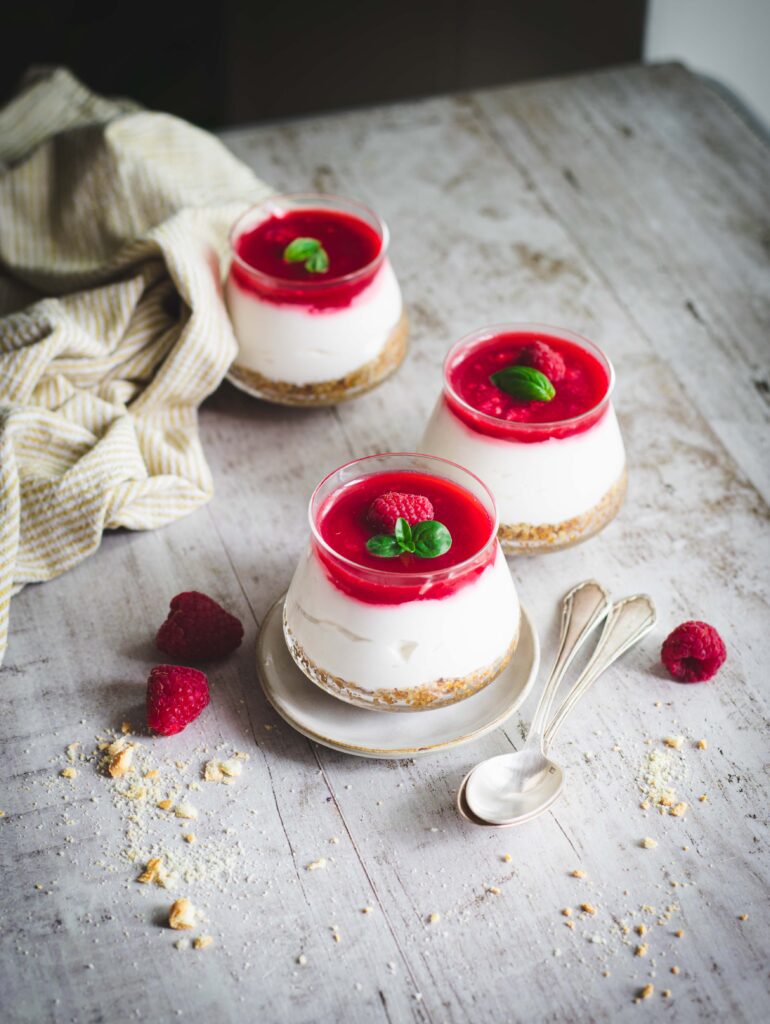Cheesecake vegana allo yogurt in vasetti su tavolo di legno con cucchiaino