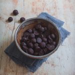 Mirtilli al cioccolato fondente in coppetta su canovaccio e tavolo in legno