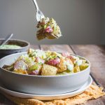 patate e ravanelli al forno con salsa ranch in piatto fondo bianco su tavolo in legno