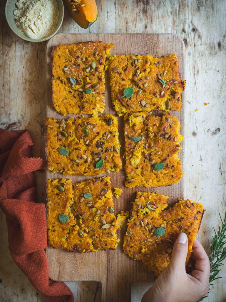 schiacciata di zucca con farina di ceci su tagliere in legno con canovaccio rosso