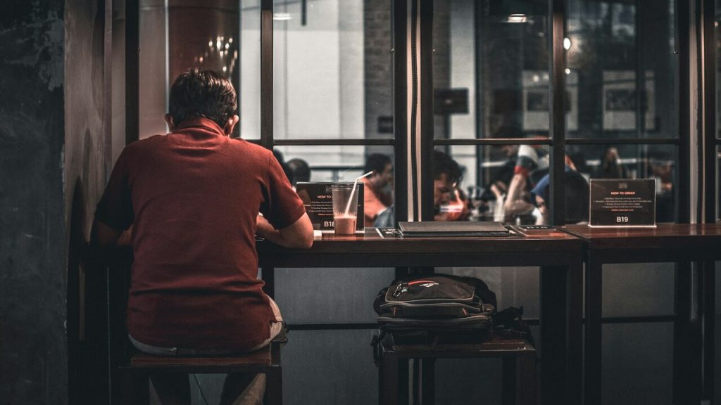 Uomo mangia da solo seduto allo sgabello di un ristorante