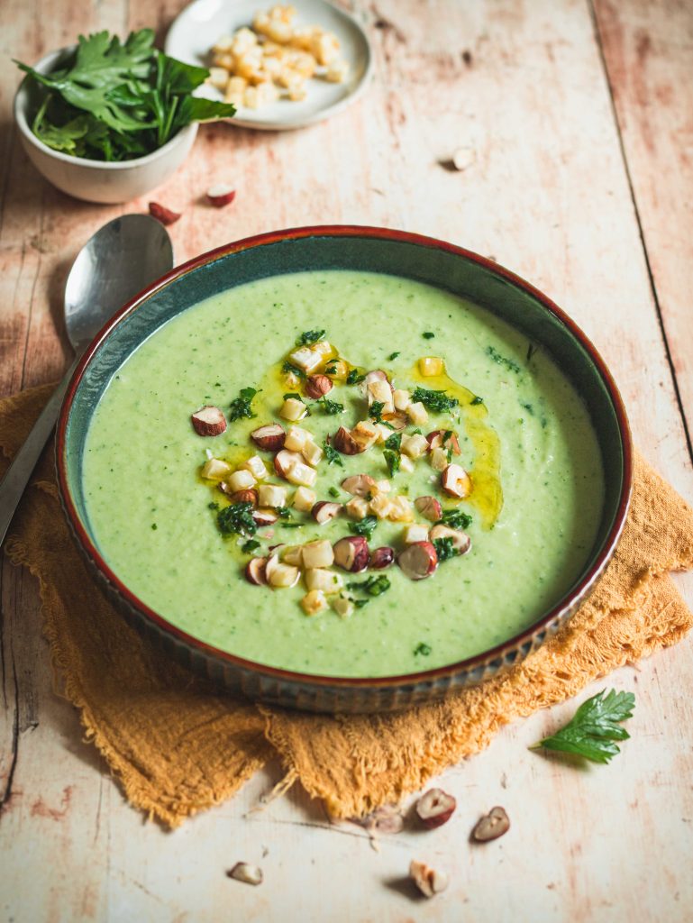 Piatto con vellutata di sedano rapa, cucchiaio e canovaccio arancione