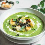 Vellutata di cavolo nero con crostini su piatto bianco