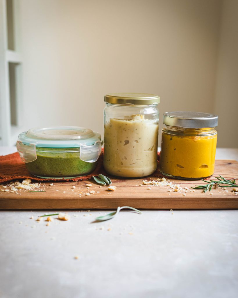 Barattolo di sugo vegetale di zucca e due barattoli di sughi vegan su tagliere