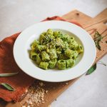 Pasta al sugo vegano con cime di rapa, pomodori e tofu su tagliere di legno e canovaccio rosso