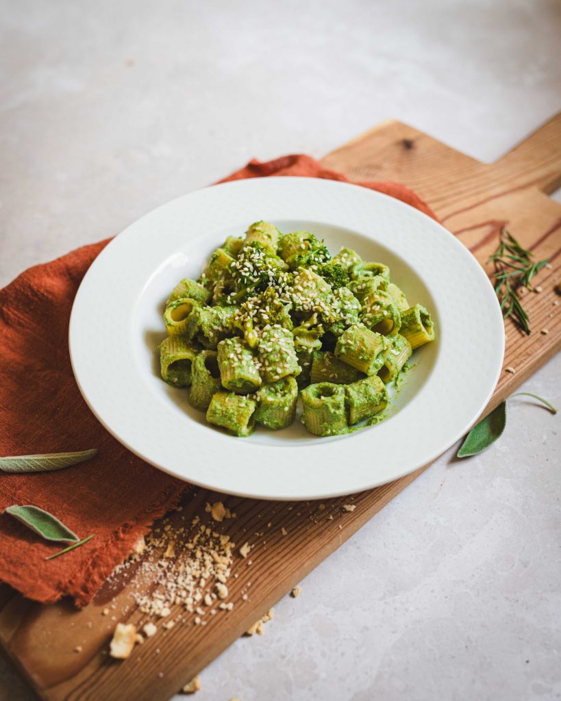 Pasta al sugo vegano con cime di rapa, pomodori e tofu su tagliere di legno e canovaccio rosso
