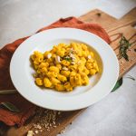 Pasta con sugo vegetale di zucca e cannellini in piatto bianco su tagliere
