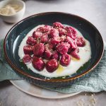 Gnocchi di barbabietola e patate su fondo di panna veg in piatto con canovaccio