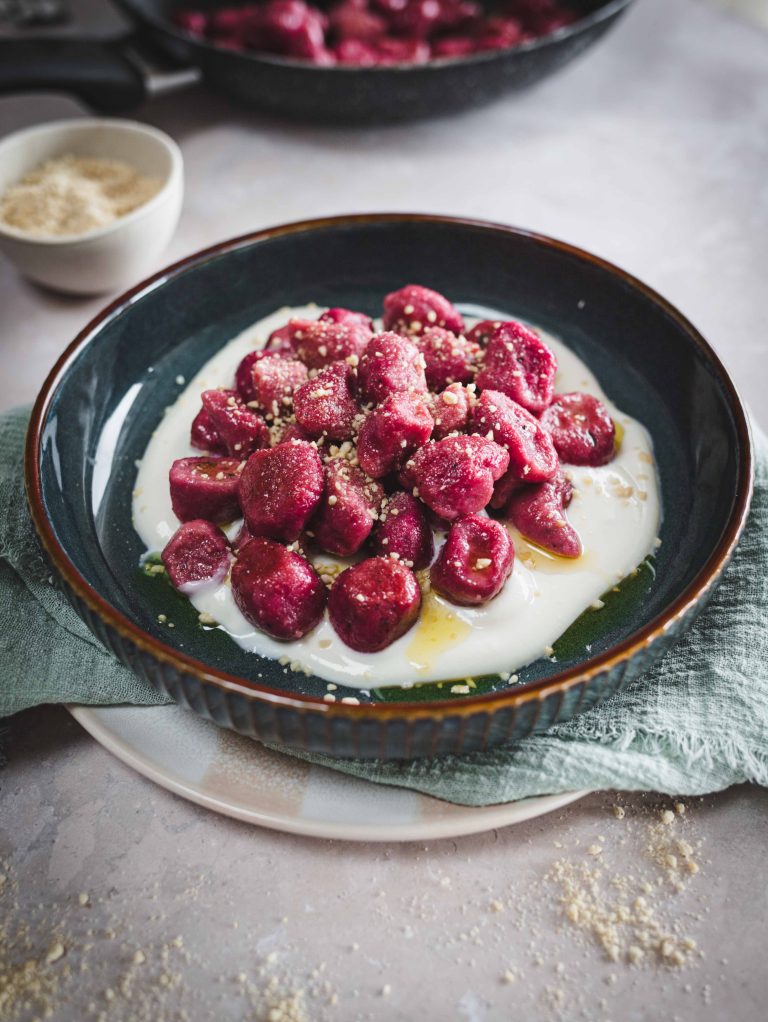 Gnocchi di barbabietola e patate su fondo di panna veg in piatto con canovaccio