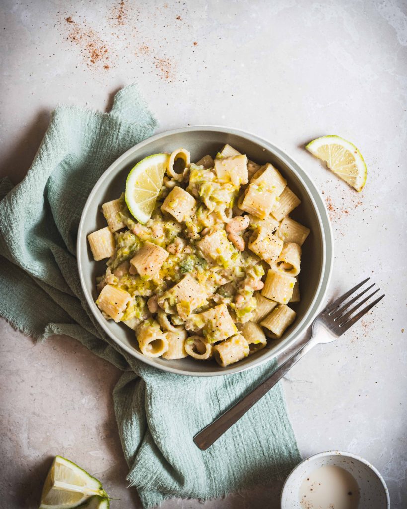 Piatto di pasta con porri, limone e cannellini su tavolo e posata