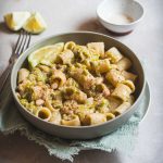 Pasta con porri, limone e cannellini in piatto fondo con canovaccio azzurro e forchetta
