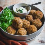 Polpette vegane di miglio, cavolfiore e cannellini con maionese veg in piatto su tavolo