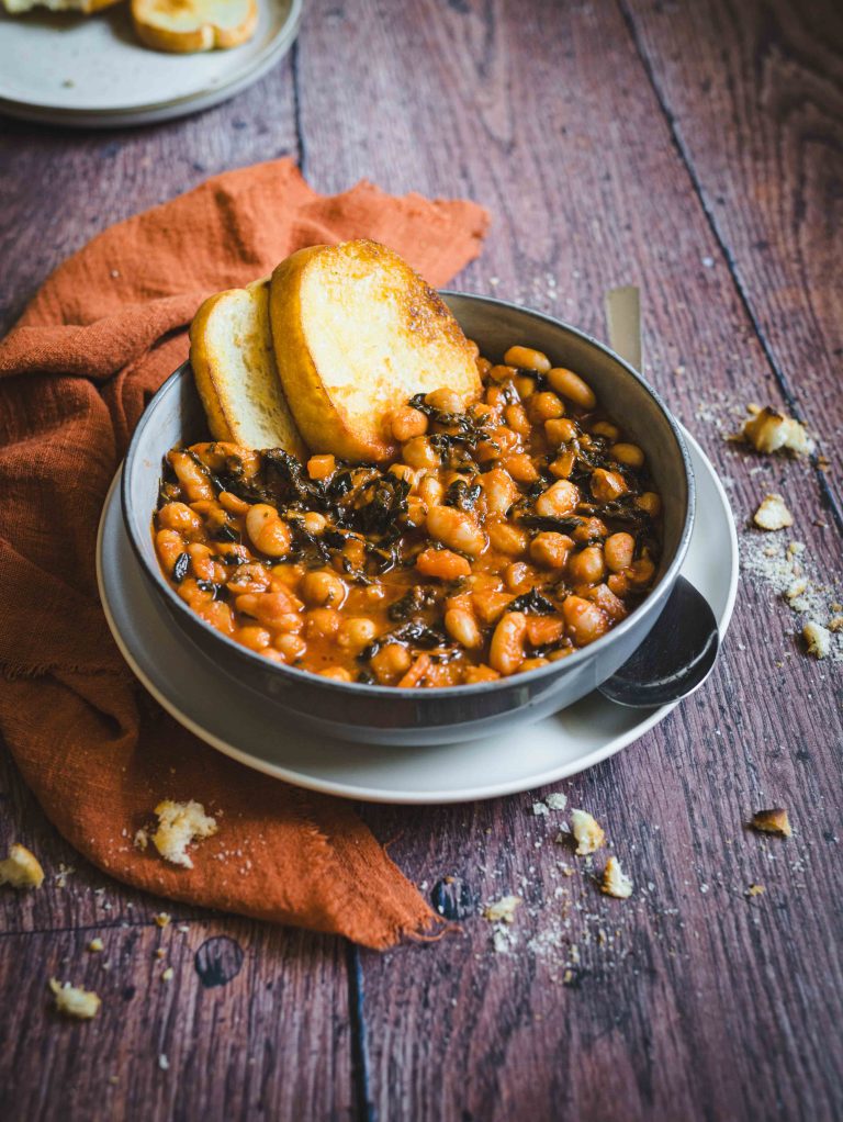 Stufato di legumi con fette di pane in piatto bianco su tavolo e canovaccio