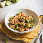 Tempeh stir fry in piatto fondo bianco con canovaccio giallo e posate